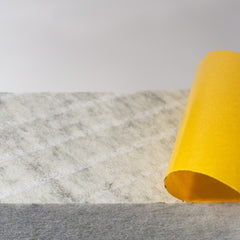 Nahaufnahme der selbstklebenden Schicht mit gelbem Schutzpapier.